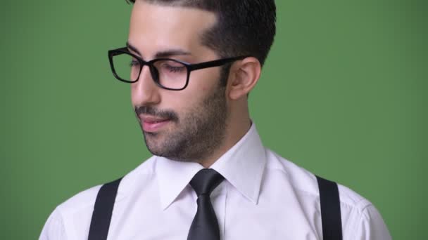 Young handsome bearded Persian businessman against green background