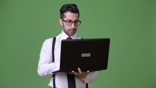 Young handsome bearded Persian businessman against green background — Stock Video