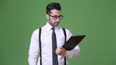 Genç yakışıklı sakallı İranlı işadamı yeşil bir arka plana dayanır