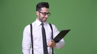 Genç yakışıklı sakallı İranlı işadamı yeşil bir arka plana dayanır