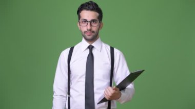 Genç yakışıklı sakallı İranlı işadamı yeşil bir arka plana dayanır
