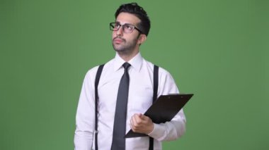 Genç yakışıklı sakallı İranlı işadamı yeşil bir arka plana dayanır