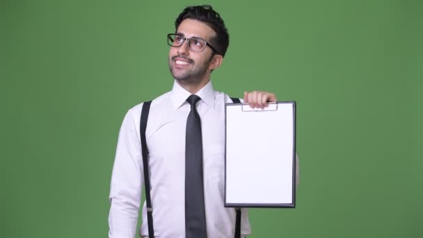 Young handsome bearded Persian businessman against green background — Stock Video