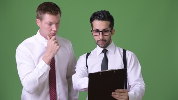 Zwei junge multiethnische Geschäftsleute, die vor grünem Hintergrund zusammenarbeiten — Stockvideo