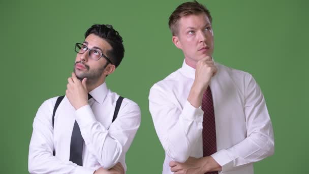Two young multi-ethnic businessmen working together against green background — Stock Video