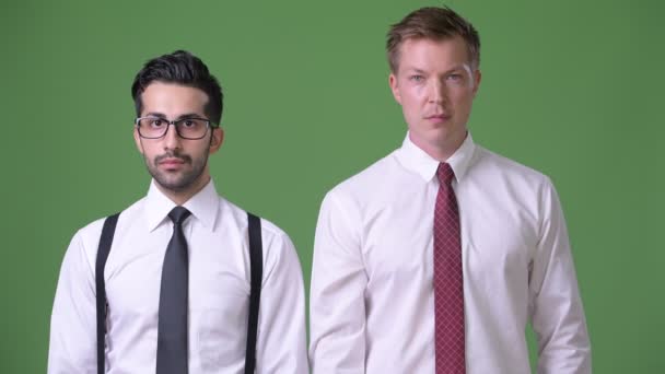 Dos jóvenes empresarios multiétnicos que trabajan juntos contra el fondo verde — Vídeos de Stock