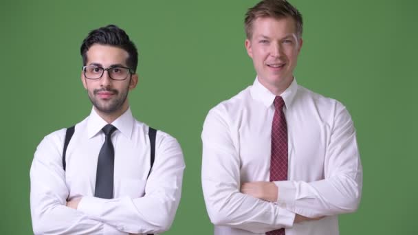 Dwaj młodzi biznesmeni wieloetnicznego, pracując razem, na zielonym tle — Wideo stockowe