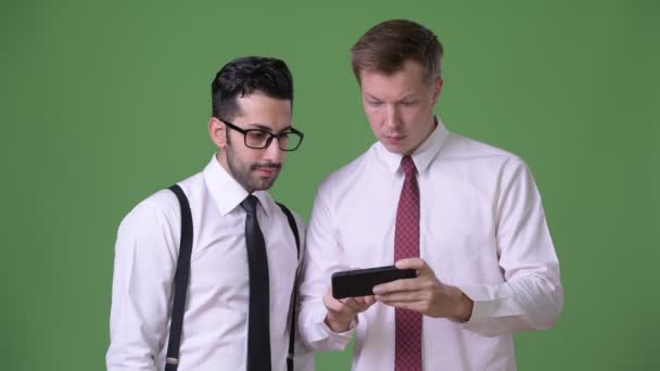 Два молодых многонациональных бизнесмена, работающих вместе на зеленом фоне — стоковое видео