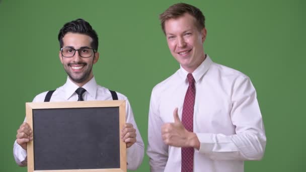 Zwei junge multiethnische Geschäftsleute, die vor grünem Hintergrund zusammenarbeiten — Stockvideo