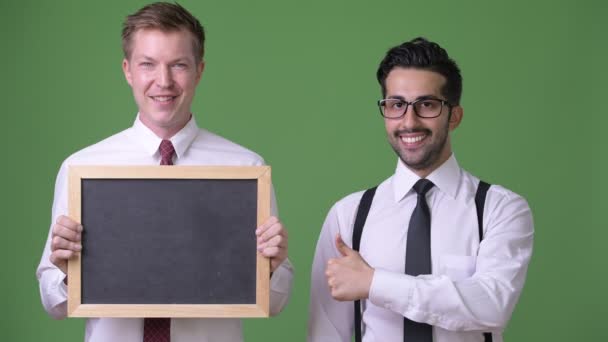 Dwaj młodzi biznesmeni wieloetnicznego, pracując razem, na zielonym tle — Wideo stockowe