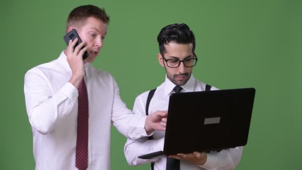 Two young multi-ethnic businessmen working together against green background — Stock Video