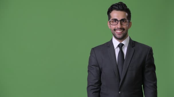 Jonge knappe bebaarde Perzisch zakenman tegen groene achtergrond — Stockvideo