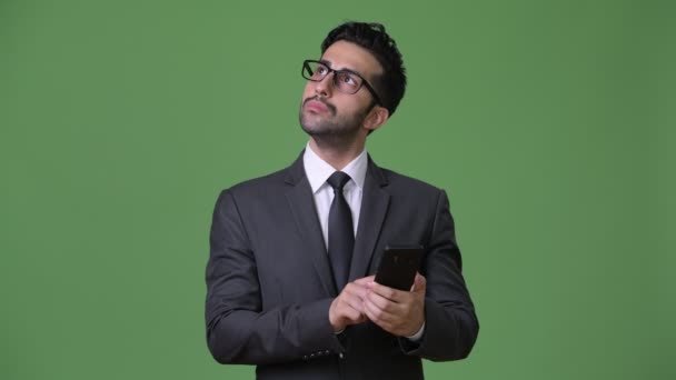 Young handsome bearded Persian businessman against green background — Stock Video