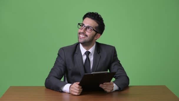 Young handsome bearded Persian businessman against green background — Stock Video