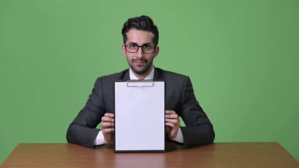 Young handsome bearded Persian businessman against green background — Stock Video