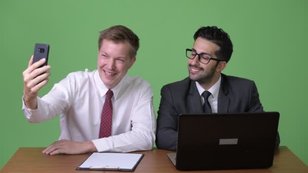 Dos jóvenes empresarios multiétnicos que trabajan juntos contra el fondo verde — Vídeo de stock