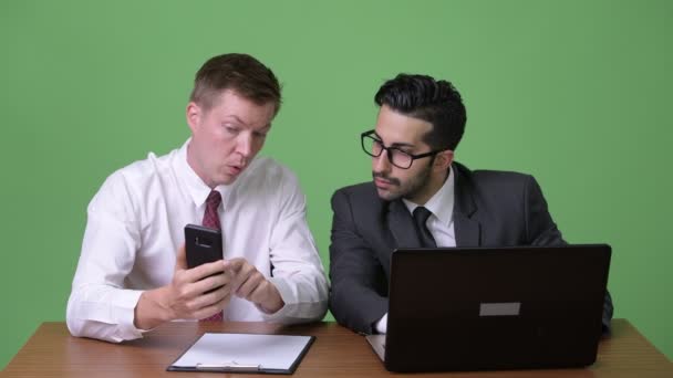 Två unga multietniska affärsmän som arbetar tillsammans mot grön bakgrund — Stockvideo