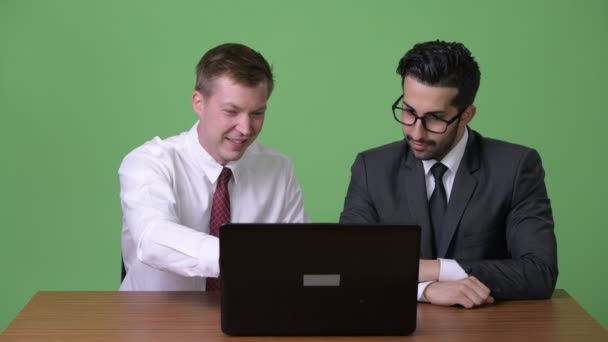 Dos jóvenes empresarios multiétnicos que trabajan juntos contra el fondo verde — Vídeo de stock