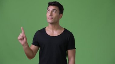 Genç yakışıklı İspanyol adam yeşil bir arka plana dayanır