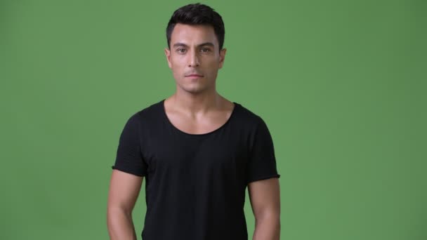 Young handsome Hispanic man against green background — Stock Video