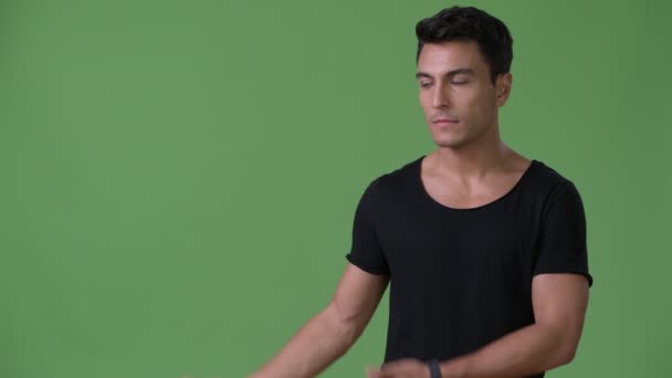 Mladý pohledný muž hispánského původu před zeleným pozadím — Stock video