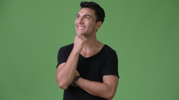 Young handsome Hispanic man against green background — Stock Video