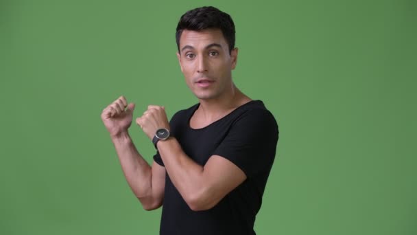Junger schöner hispanischer Mann vor grünem Hintergrund — Stockvideo
