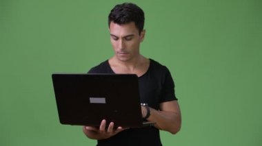 Genç yakışıklı İspanyol adam yeşil bir arka plana dayanır