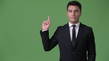 Genç yakışıklı İspanyol işadamı yeşil bir arka plana dayanır