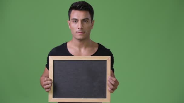 Молодой красивый латиноамериканец на зеленом фоне — стоковое видео