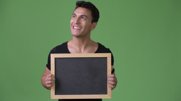 Genç yakışıklı İspanyol adam yeşil bir arka plana dayanır — Stok video
