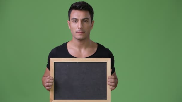 年轻英俊的拉美裔男子反对绿色背景 — 图库视频影像