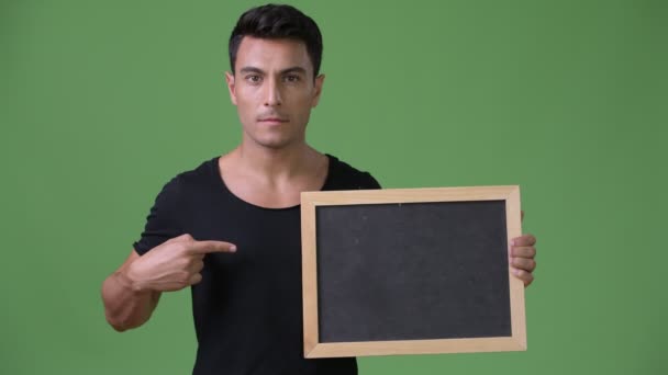 Young handsome Hispanic man against green background — Stock Video