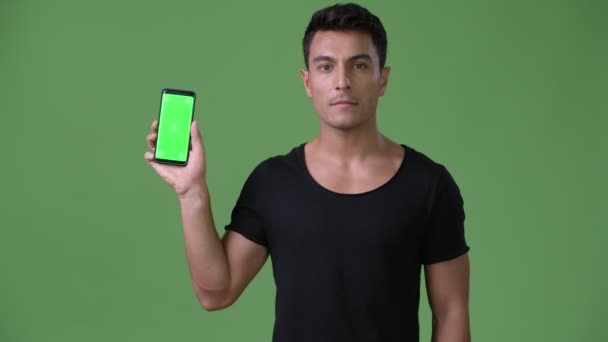 Young handsome Hispanic man against green background — Stock Video