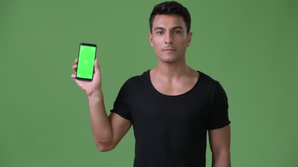 Young handsome Hispanic man against green background — Stock Video