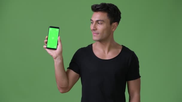 Young handsome Hispanic man against green background — Stock Video