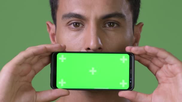 Ung vacker Hispanic man mot grön bakgrund — Stockvideo