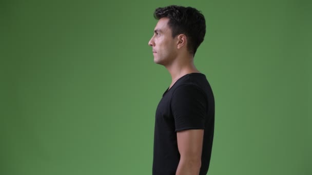 Jonge knappe man van de Hispanic tegen groene achtergrond — Stockvideo
