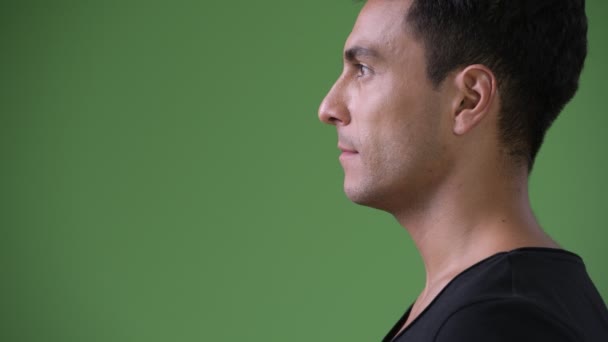 Young handsome Hispanic man against green background — Stock Video