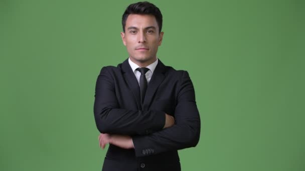 Young handsome Hispanic businessman against green background — Stock Video