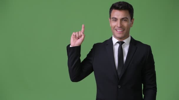 Young handsome Hispanic businessman against green background — Stock Video