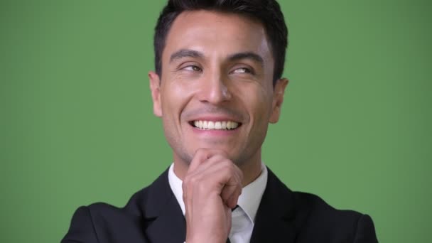 Young handsome Hispanic businessman against green background — Stock Video