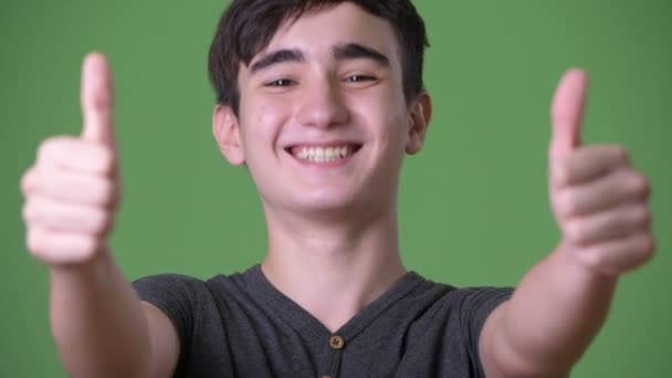 Young handsome Iranian teenage boy against green background — Stock Video