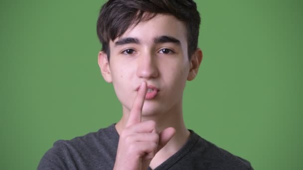 Young handsome Iranian teenage boy against green background — Stock Video