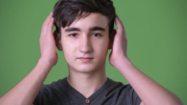 Молодой красивый иранский подросток на зеленом фоне — стоковое видео