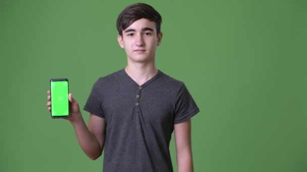 Mladý pohledný íránské dospívající chlapec proti zeleným pozadím — Stock video