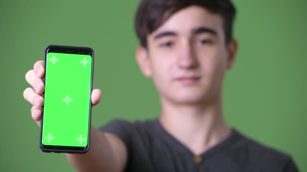 Unga stiliga iranska tonårspojke mot grön bakgrund — Stockvideo