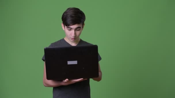 Young handsome Iranian teenage boy against green background — Stock Video