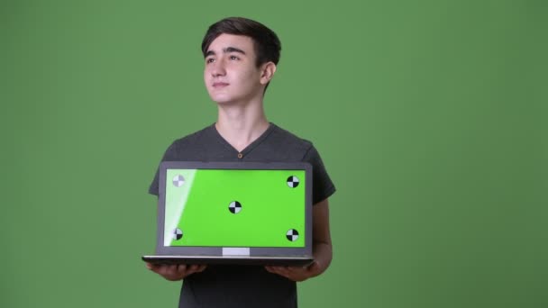 Young handsome Iranian teenage boy against green background — Stock Video