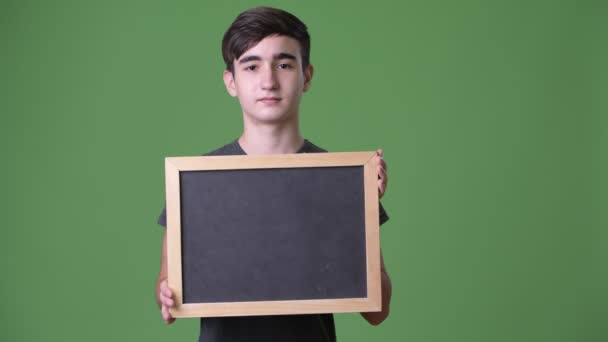 Young handsome Iranian teenage boy against green background — Stock Video